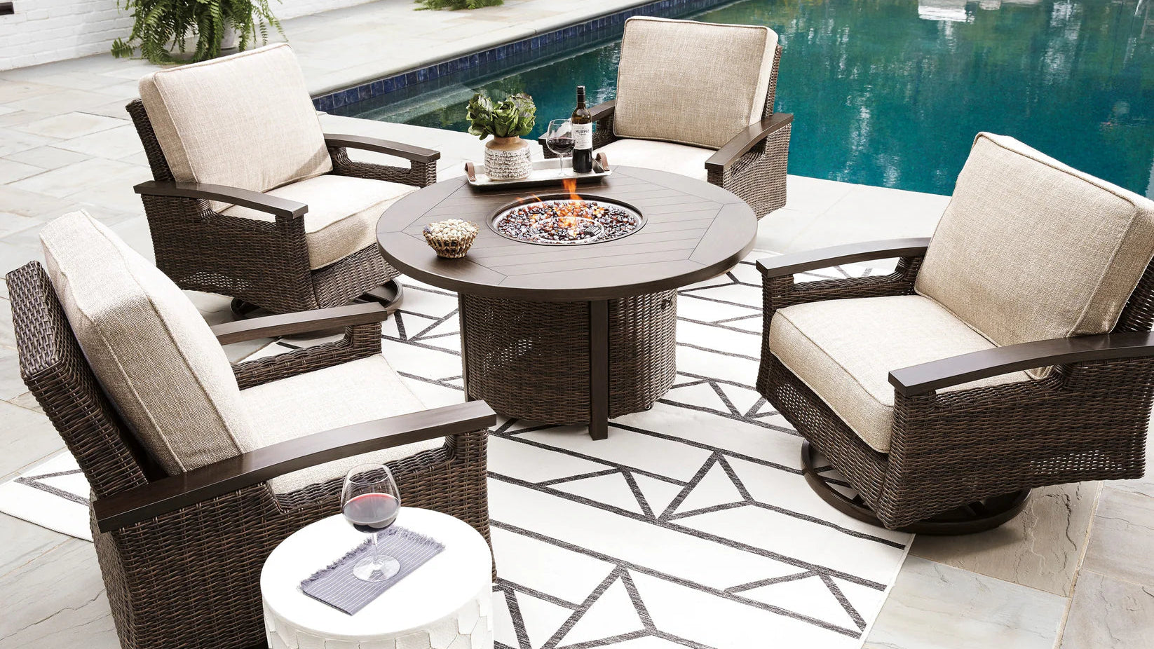Outdoor patio furniture set with a fire pit table by a pool.