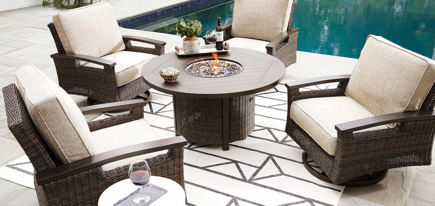 Outdoor patio set with wicker chairs and a fire pit table by a pool.