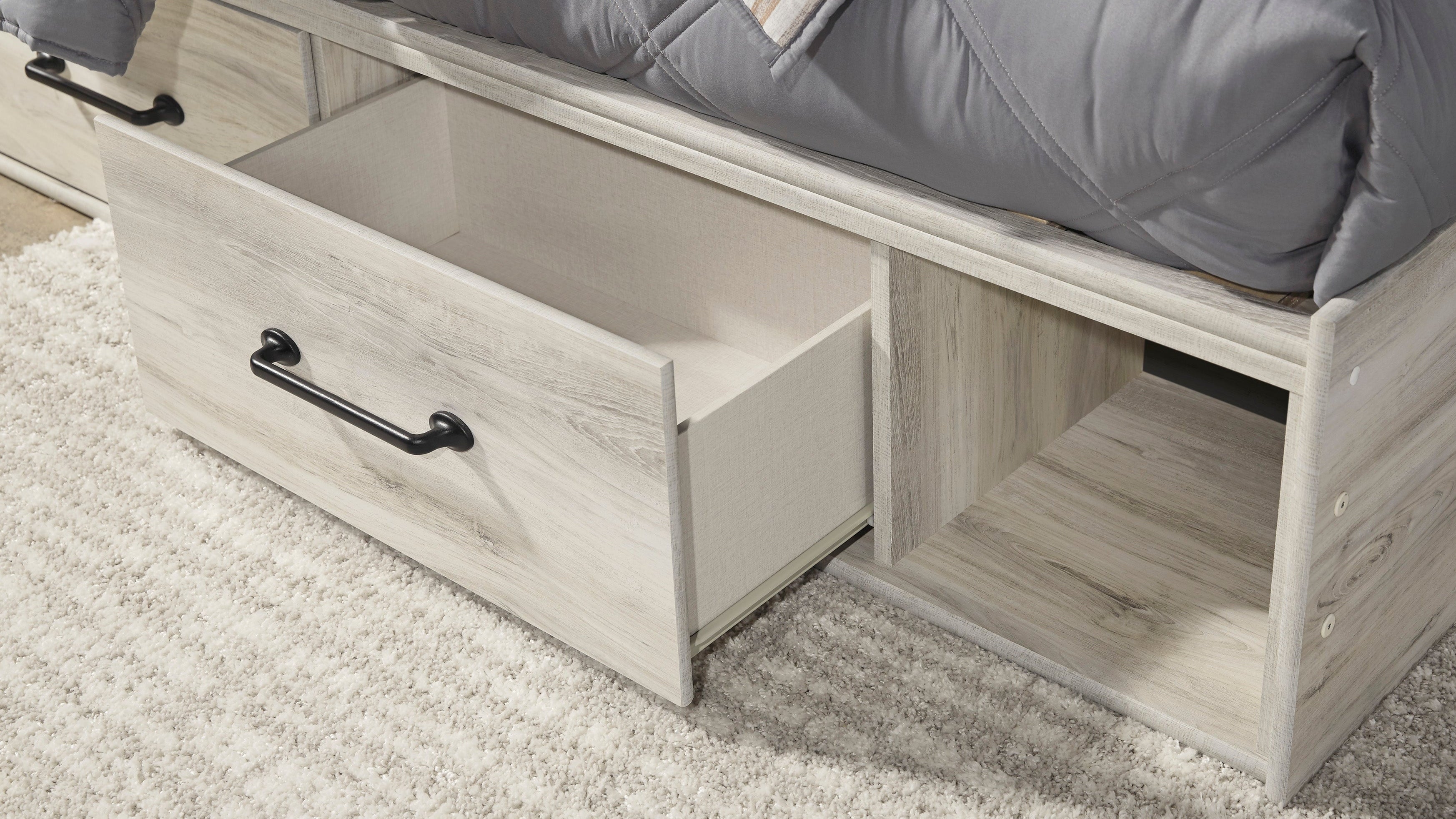 Wooden bed with open drawer on a carpeted floor
