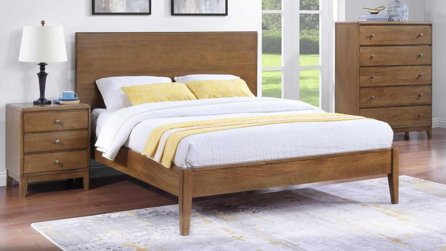 Wooden bed with white bedding and yellow blanket in a room with a dresser and lamp.