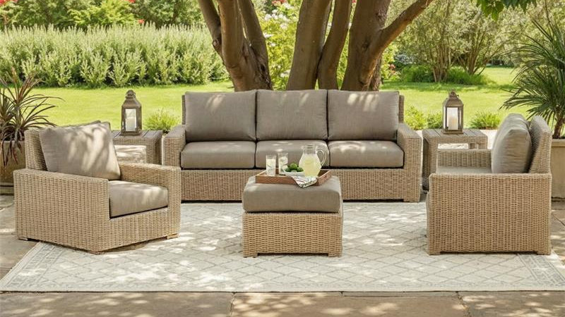 Outdoor patio furniture set with gray cushions on a stone patio.