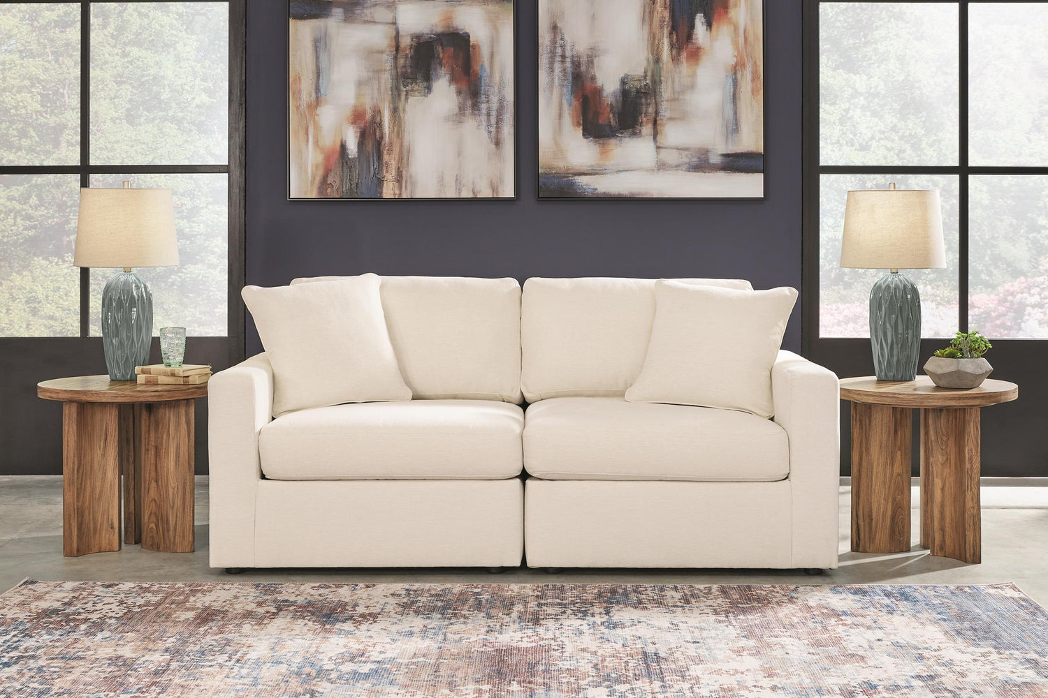 Beige sofa in a living room with abstract art and side tables.