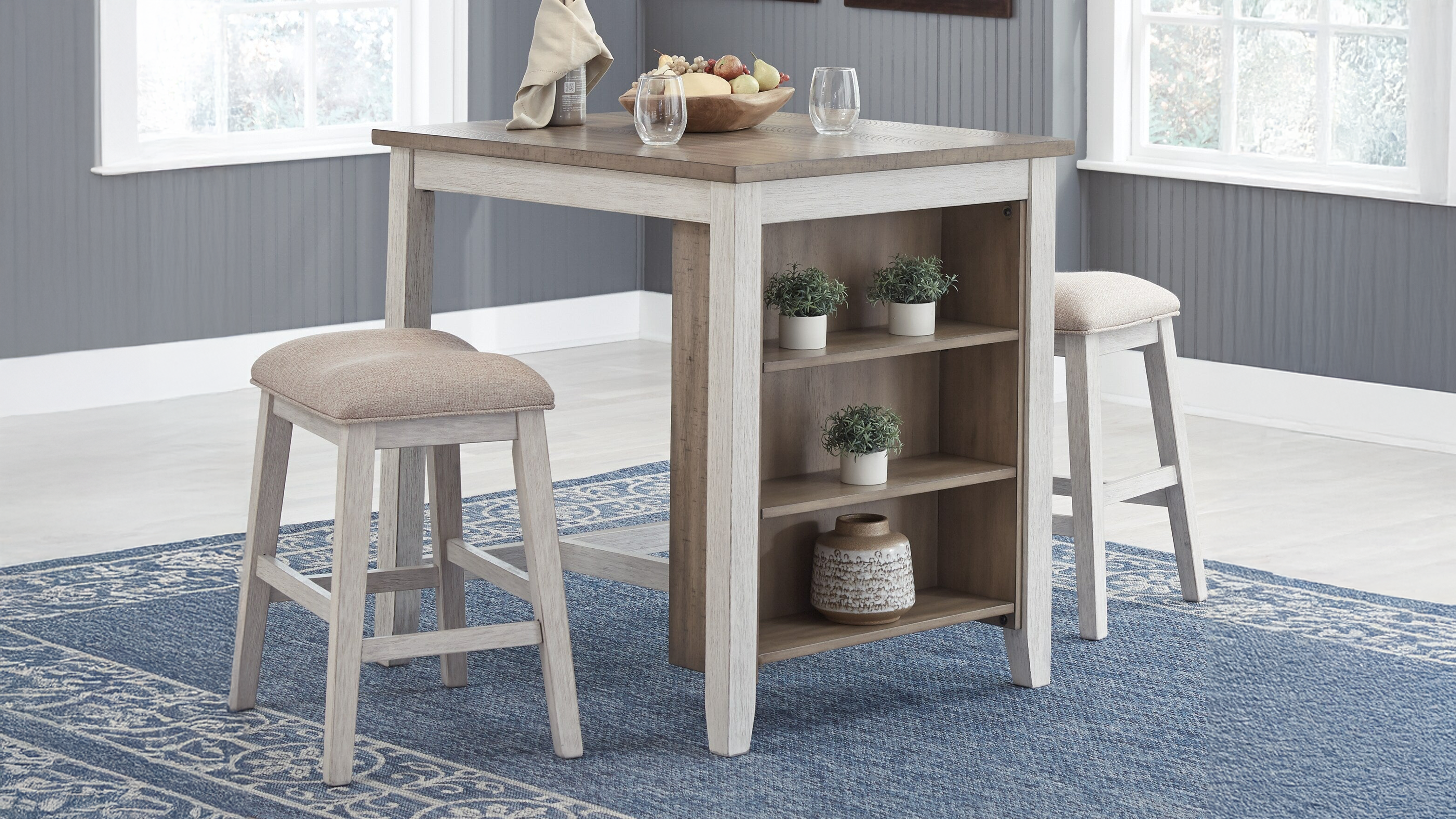 Kitchen table with shelves and stools in a room with blue carpet and white walls.