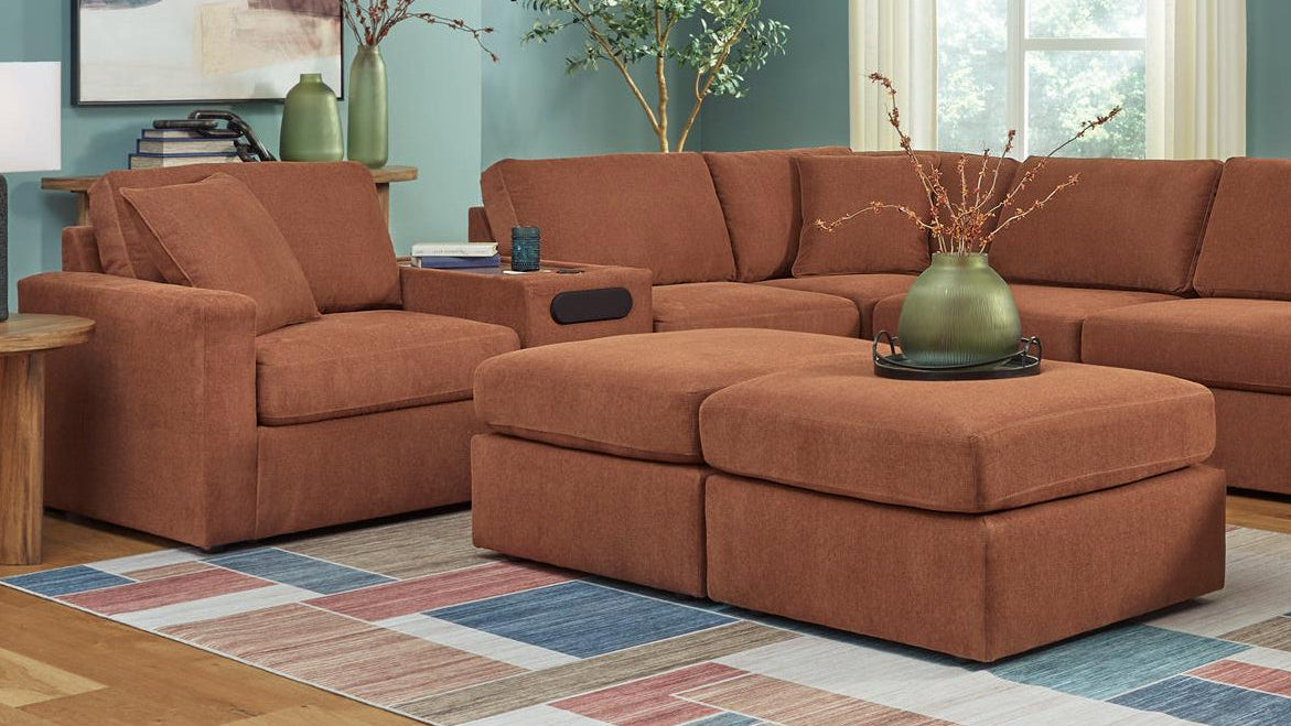 Brown sectional sofa in a living room with a colorful rug and decorative items.
