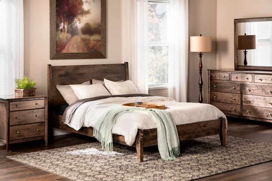 Bedroom with wooden furniture including a bed, nightstands, and a dresser.