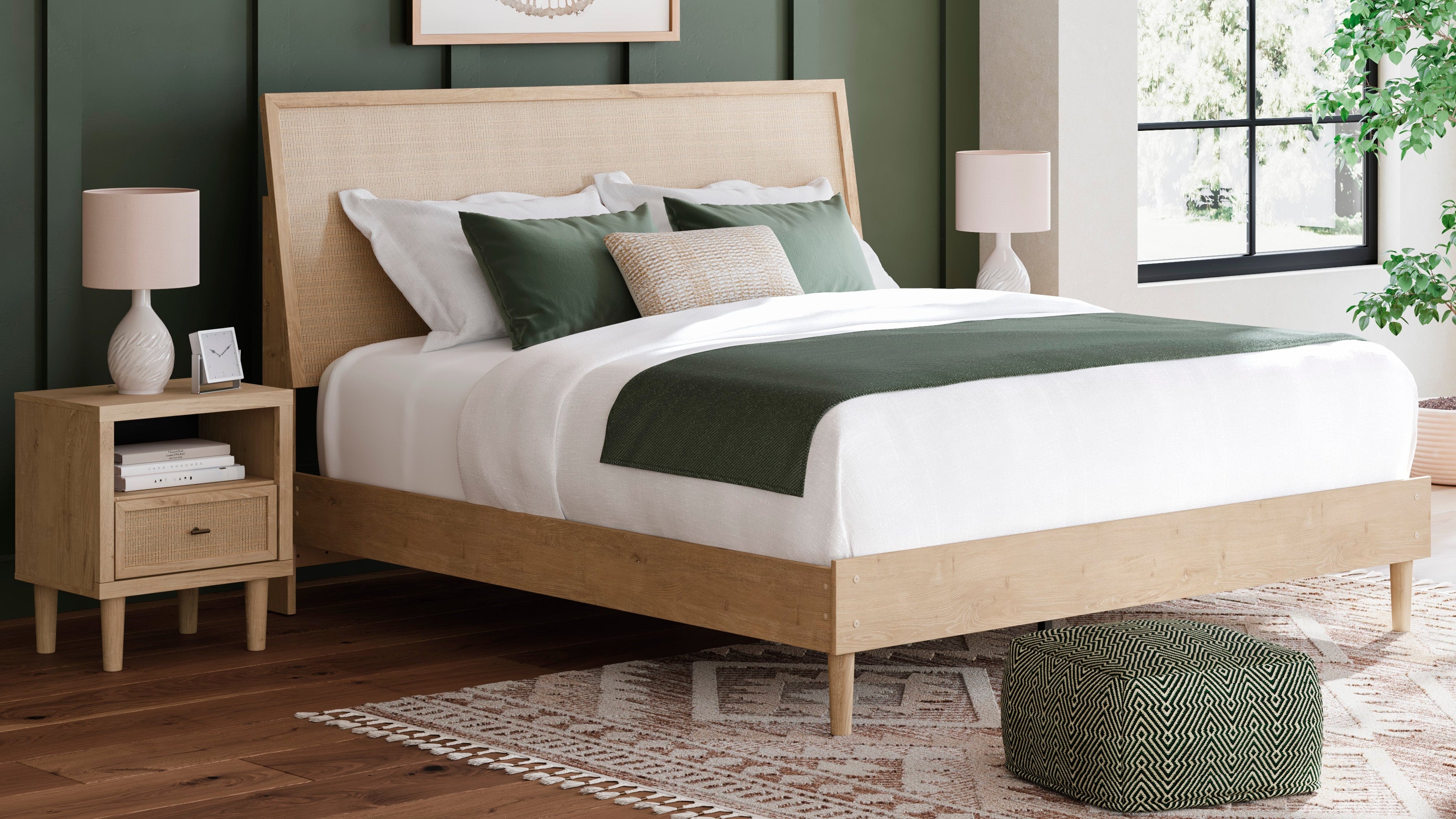 Neatly made bed with beige headboard in a room with green walls, a lamp, and a plant.
