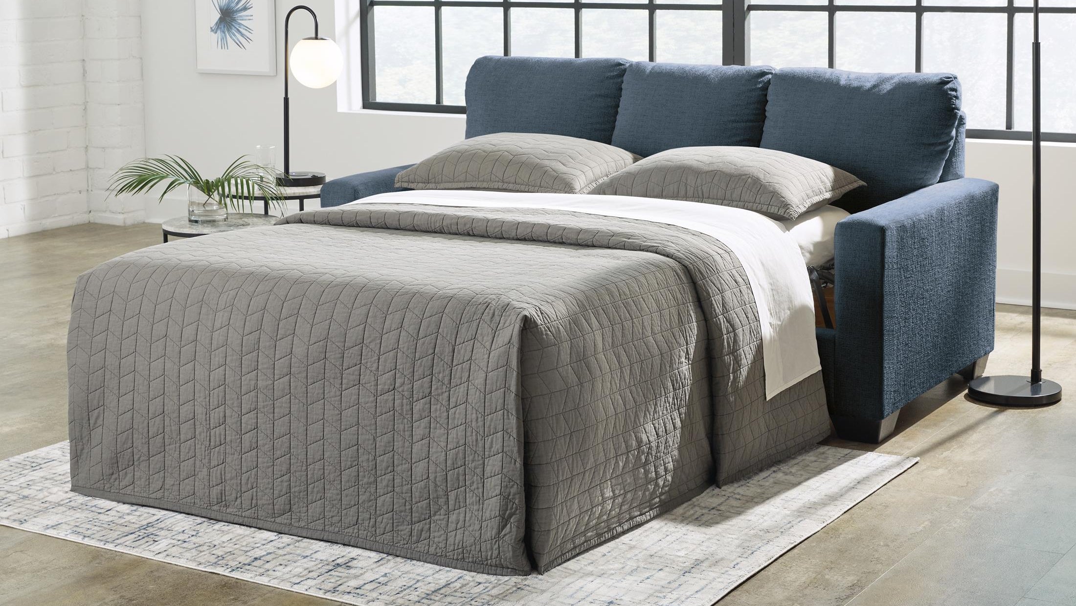 Blue sofa with pull out bed in a room setting.